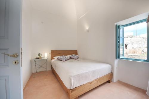 una piccola camera da letto con un letto e una finestra di Santorinio Yellow House a Éxo Goniá