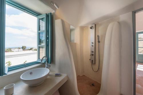a bathroom with a sink and a shower and a window at Santorinio Yellow House in Éxo Goniá