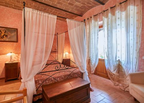 a bedroom with a bed with white curtains at Agriturismo Barbicate in Saturnia