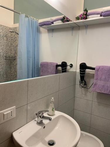 a bathroom with a sink and a mirror and purple towels at Zia Regina in Ripatransone