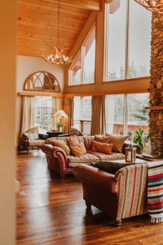 a large living room with leather furniture and windows at Ambleside Lodge Bed & Breakfast in Canmore