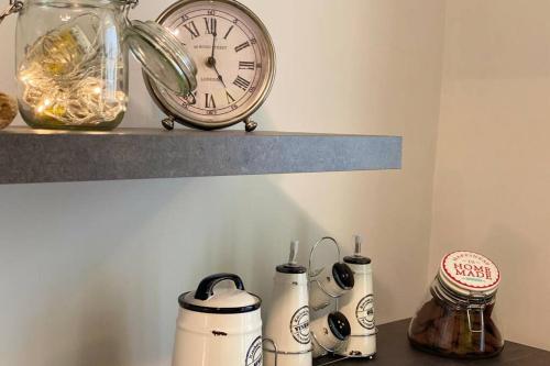 a clock sitting on top of a shelf next to bottles at Spa Tiny Love Apartment close to Milan-Como-Malpensa in Saronno