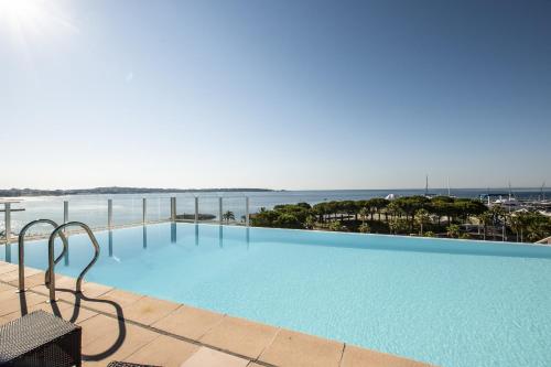 a large swimming pool with the ocean in the background at Le palais napoleon in Golfe-Juan