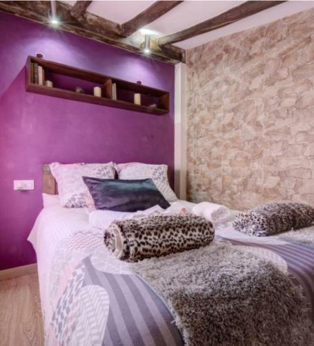 two beds in a room with a purple wall at El Estudio Lila de Ubrique in Ubrique