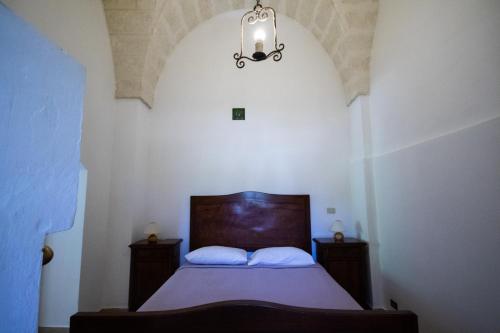a bedroom with a bed and a chandelier at Masseria Parco di Castro in Montalbano