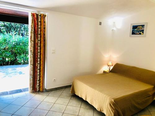 a bedroom with a bed and a large window at Villa Les Lieges de Palombaggia in Porto-Vecchio