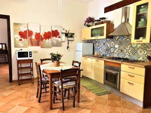 una cucina con tavolo, sedie e piano cottura di Villa Siciliana con piscina "Dal PICCIOTTO" a Marsala