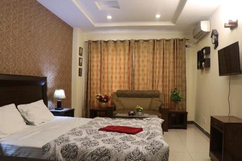 Cozy Studio Apartment In Bahria town في روالبندي: غرفة نوم مع سرير وفوط حمراء عليه