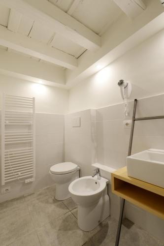 a white bathroom with a toilet and a sink at Piano Tre in Verona