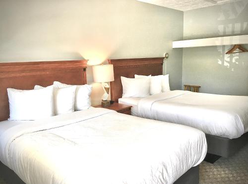 two beds in a hotel room with white sheets at Empire Lakeshore Inn in Empire