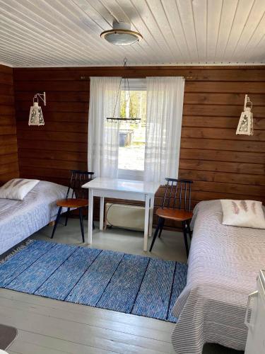 a room with two beds and a table with chairs at Huhtaniemen Mökkikylä in Veteli
