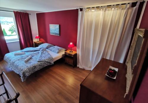 1 dormitorio con paredes rojas, 1 cama y 1 mesa en Apartments Volče en Tolmin