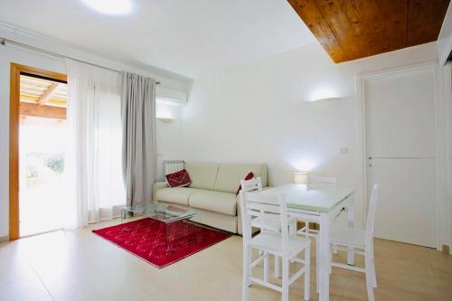 sala de estar con sofá, mesa y sillas en Cala Azul Residence B&B, en Alghero