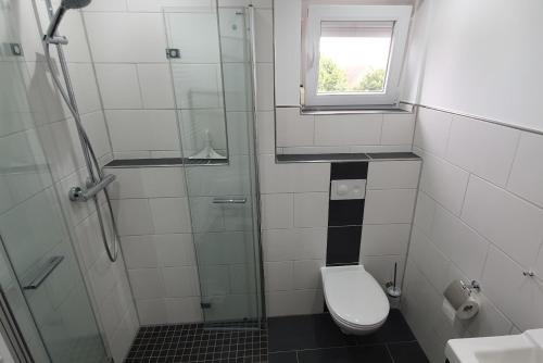a bathroom with a toilet and a glass shower at Ferienwohnung Strandjuwel am Strand in Norddeich