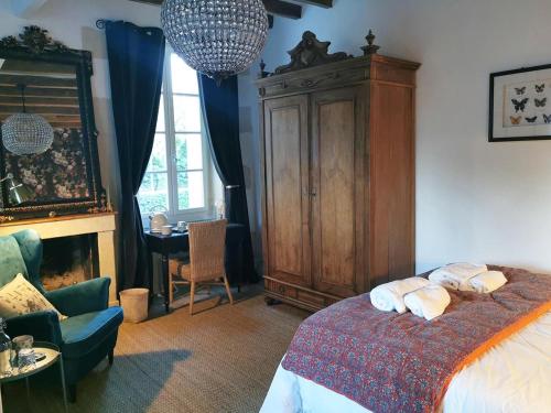 een slaapkamer met een bed en een grote houten kast bij Quatre Chats sous un Pin in Le Thoureil