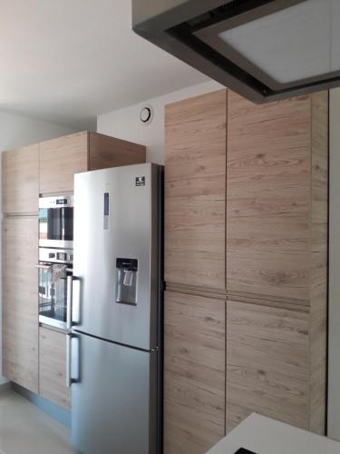 cocina con nevera y armarios de madera en Appartement Rêve-Catalan 2 chambres en Perpiñán