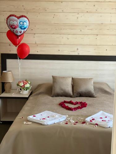 a bed with two hearts balloons and two towels at Chayka Resort in Odesa