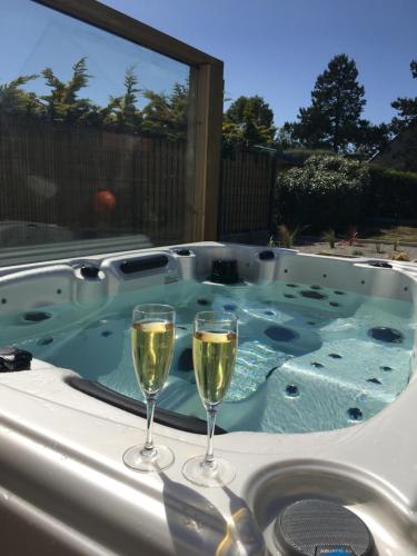 two glasses of wine sitting on a hot tub at Escale à 2 dans le Skiff, bord de mer et spa in Barneville-Carteret