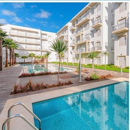 una piscina frente a un edificio de apartamentos en Magnifique Appartement balnéaire à Bouznika avec piscine, en Bouznika