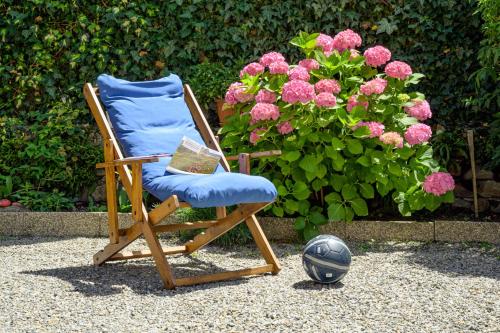 a blue chair sitting next to a plant with pink flowers at Le Rondini in Tirano
