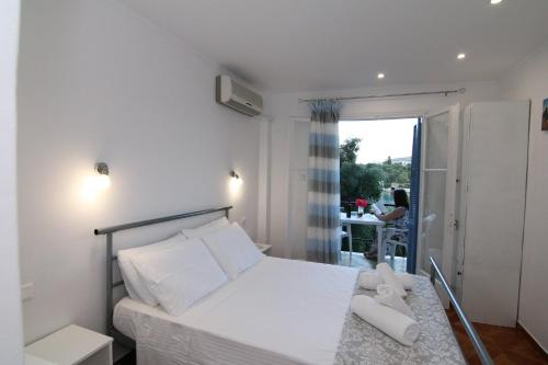 a bedroom with a white bed and a balcony at Sea Breeze in Paleokastritsa