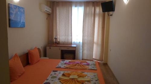 een slaapkamer met een bed, een raam en een tafel bij Ivanovi Guest House in Primorsko