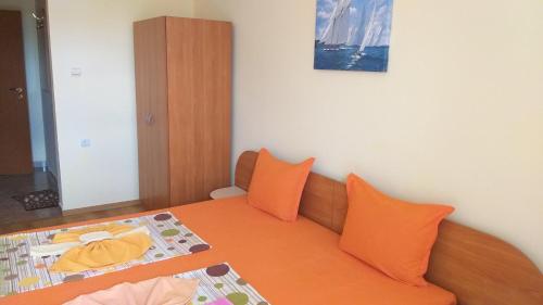 um quarto com uma cama com almofadas laranja em Ivanovi Guest House em Primorsko