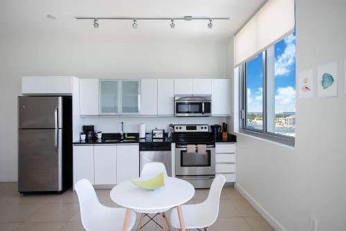 a white kitchen with a table and chairs at Bluebird Suites Monte Carlo Miami Beach in Miami Beach