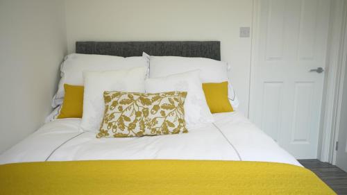 a white bed with a yellow blanket and a pillow at Palm House in Widnes