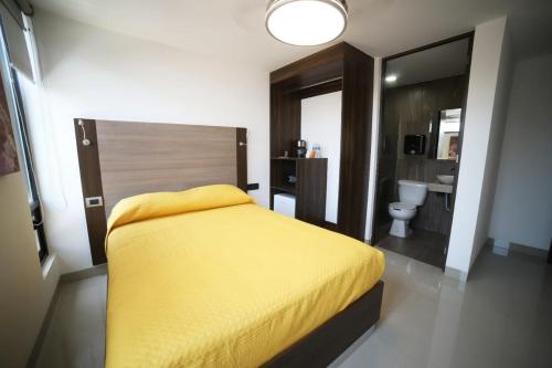 a bedroom with a yellow bed and a bathroom at Tepeyac 402 in León