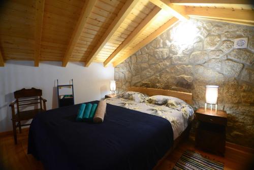 a bedroom with a bed and a stone wall at Casa do Guardado in Monsanto