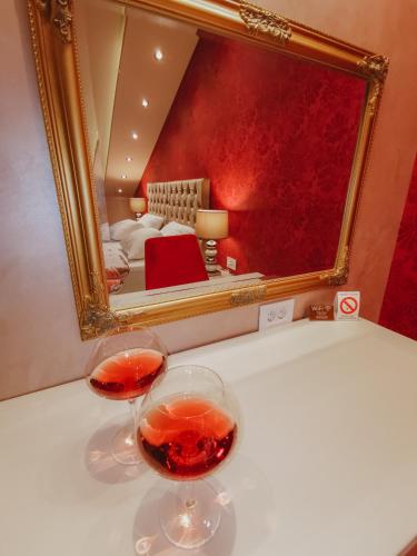 two glasses of wine sitting on a table in front of a mirror at Vazdušna Banja in Niš