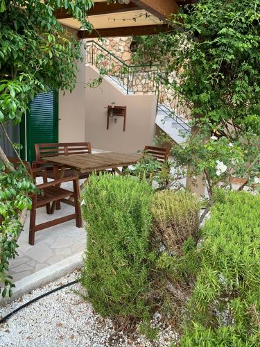 a wooden table and benches in a garden at Katarina Apartments Kefalonia - Sea View in Kefallonia
