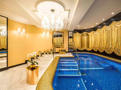 a swimming pool in a hotel lobby with a chandelier at Bachleda Luxury Hotel Krakow MGallery Hotel Collection in Krakow