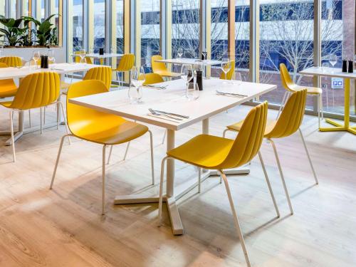 a table and chairs in a restaurant with yellow chairs at ibis Styles East Perth in Perth