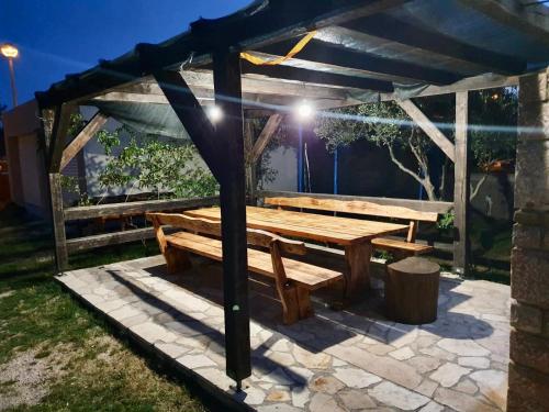 a wooden picnic table under a pergola at night at Apartman Petar in Ražanac