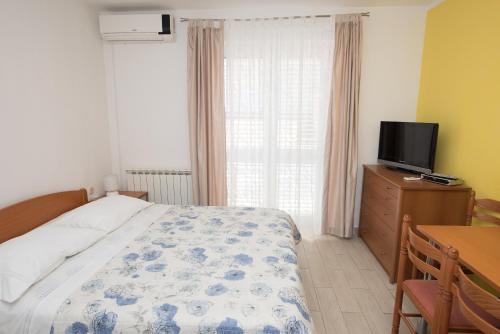 a bedroom with a bed and a tv and a window at Apartments Lovrić in Vodice
