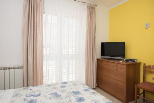 a bedroom with a bed and a television on a dresser at Apartments Lovrić in Vodice