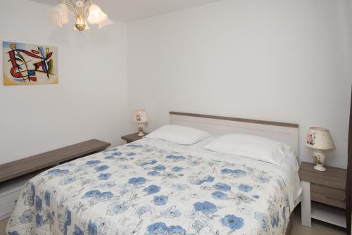 a bedroom with a bed with a blue and white comforter at Apartments Lovrić in Vodice