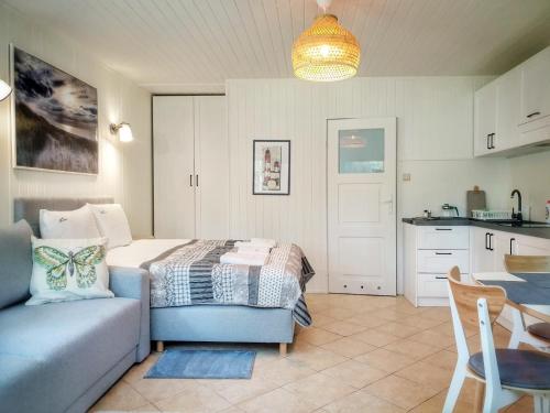 a bedroom with a bed and a couch and a kitchen at Mistral przy plaży Domki całoroczne in Ustka
