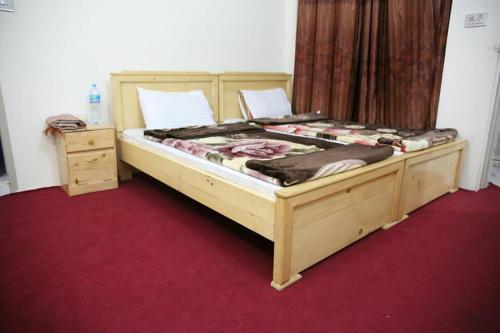a large wooden bed in a room with a red carpet at FR Darya E Swat Hotel in Mingora