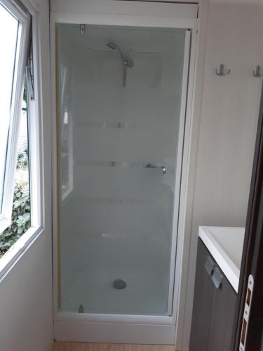 La salle de bains est pourvue d'une douche blanche et d'une fenêtre. dans l'établissement mobil-home camping 4 ****, à Vic-la-Gardiole