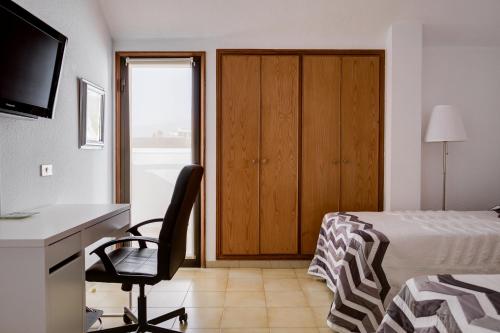 a bedroom with a bed and a desk and a chair at Melo sur in Playa de las Americas