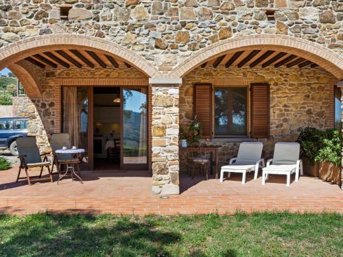 um edifício de pedra com um pátio com cadeiras e uma mesa em Belvilla by OYO Casa Sugheri em Suvereto