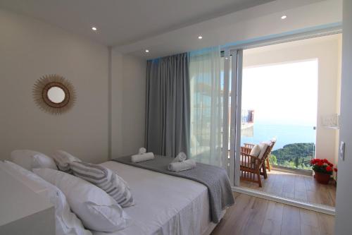 een slaapkamer met een bed en een groot raam bij Lakones Deluxe Suites in Lákones