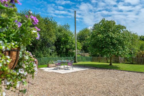 a patio with a table and chairs in a garden at Nutley Farm in Winfrith Newburgh
