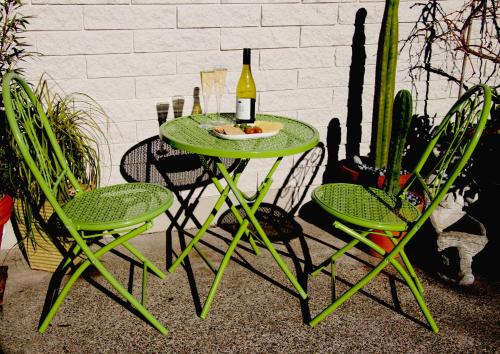 uma mesa verde com duas cadeiras e uma garrafa de vinho em The Birch Tree B&B em Motueka