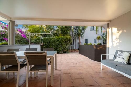 a patio with a table and chairs and a couch at Gosamara Apartments in Byron Bay