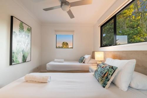 two beds in a room with two windows at Gosamara Apartments in Byron Bay