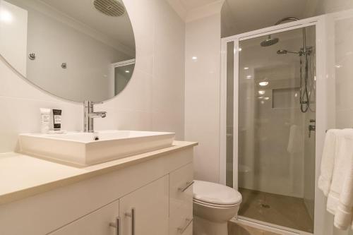 a white bathroom with a sink and a shower at Gosamara Apartments in Byron Bay